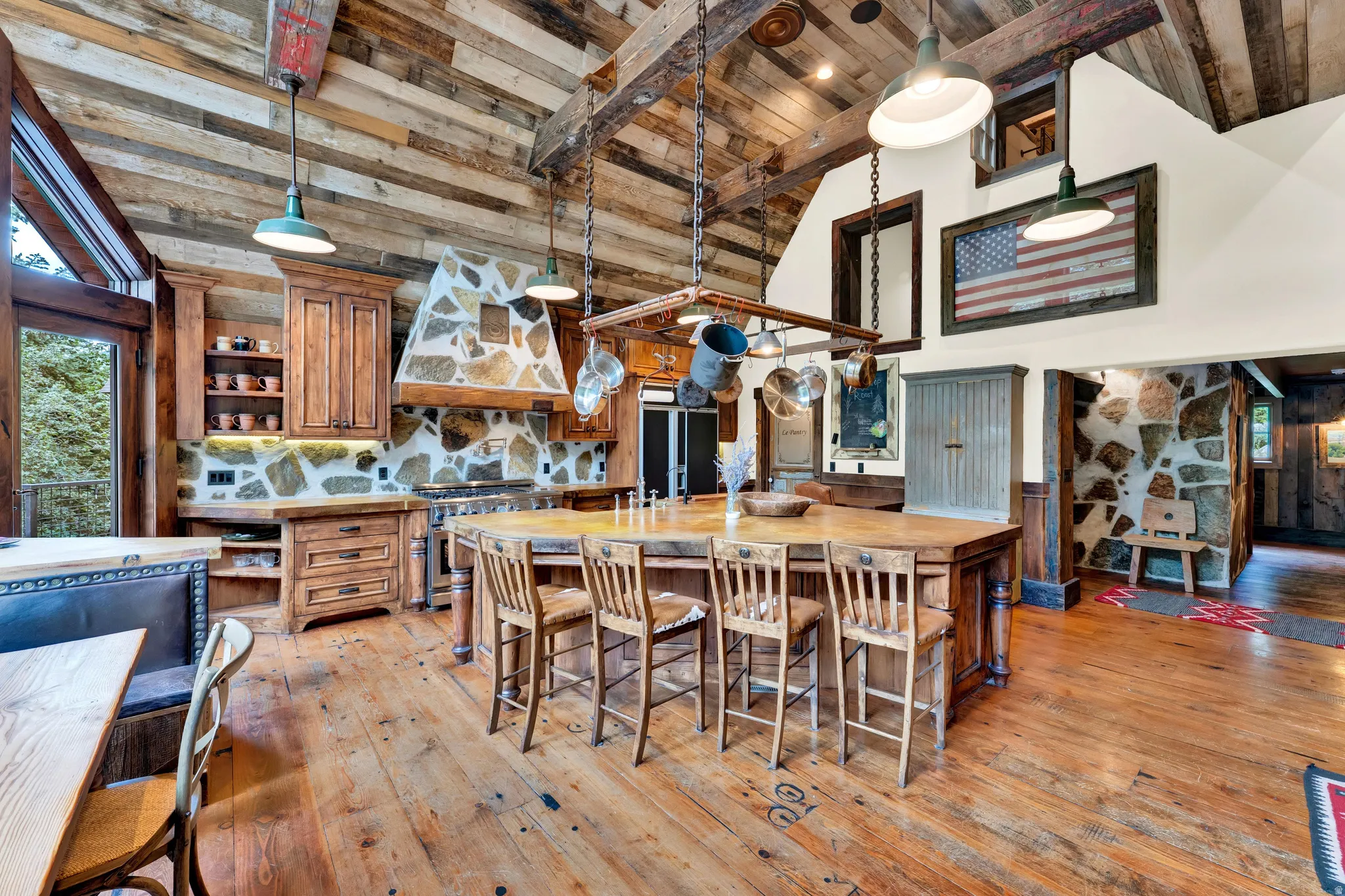 Expansive kitchen featuring wood-finish flooring, stone backsplash, rich wood cabinetry, and a substantial center island with seating