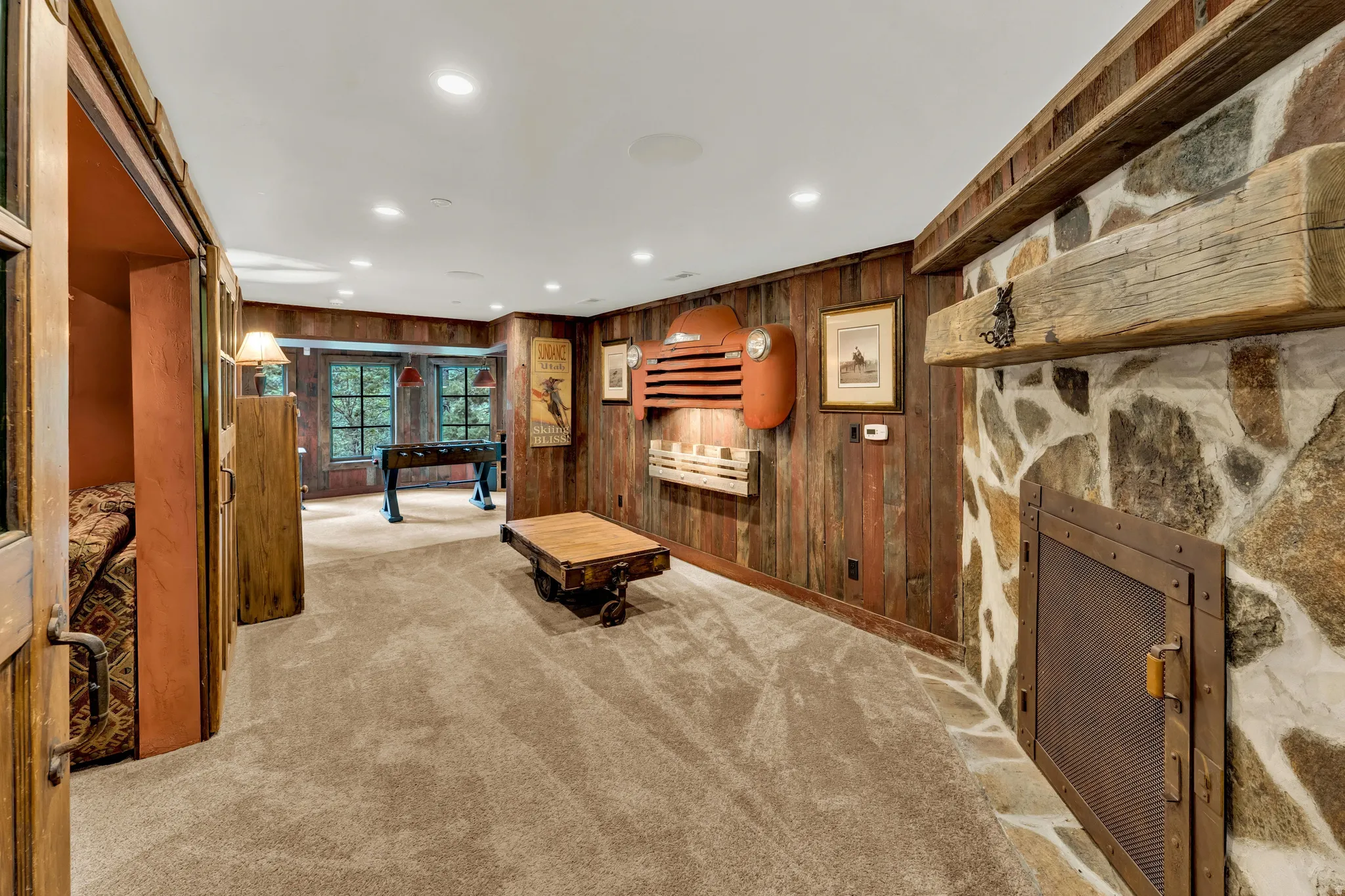 Recreation room featuring a stone fireplace with a substantial wood mantel, wood paneling, and recessed lighting