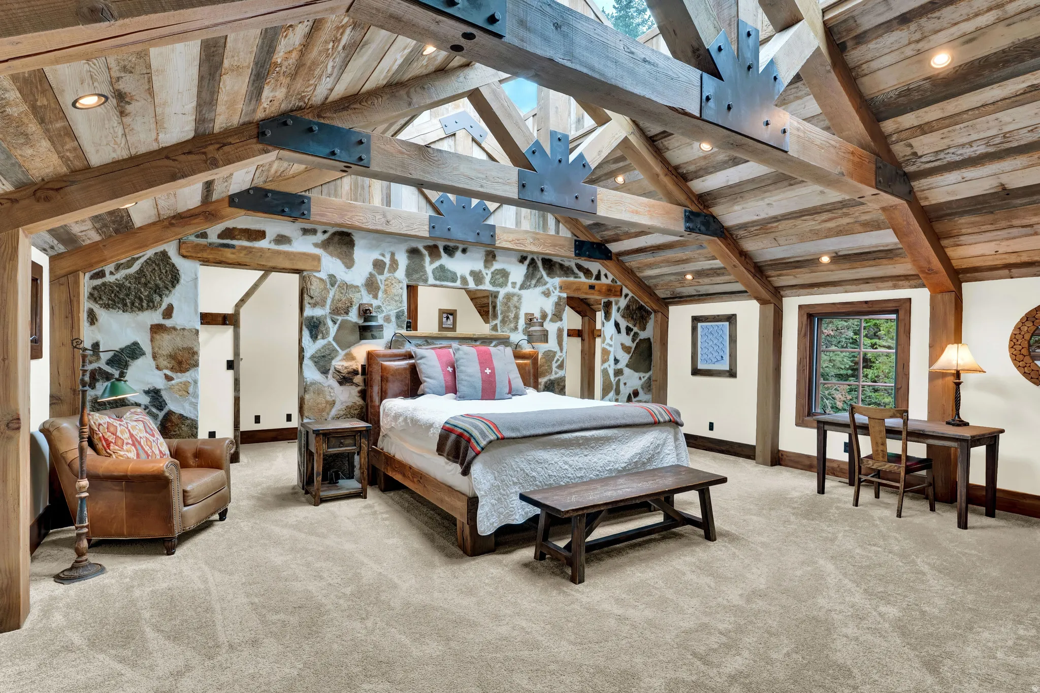 Primary Bedroom Suite featuring exposed wood-beam cathedral ceiling, abundant natural light from multiple windows, wood-finish flooring, and built-in wall sconces