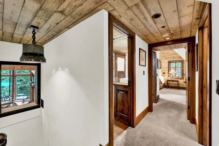 Rustic wood beam ceiling and hallway featuring rich wood-finish doors and frames, neutral carpeting, and recessed lighting throughout