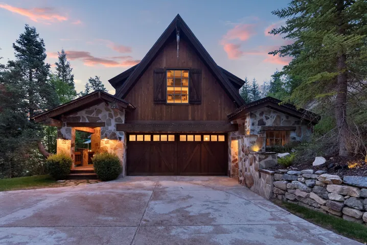 Modern A-frame residence featuring a striking dark wood and stone exterior with illuminated multi-pane gable window
