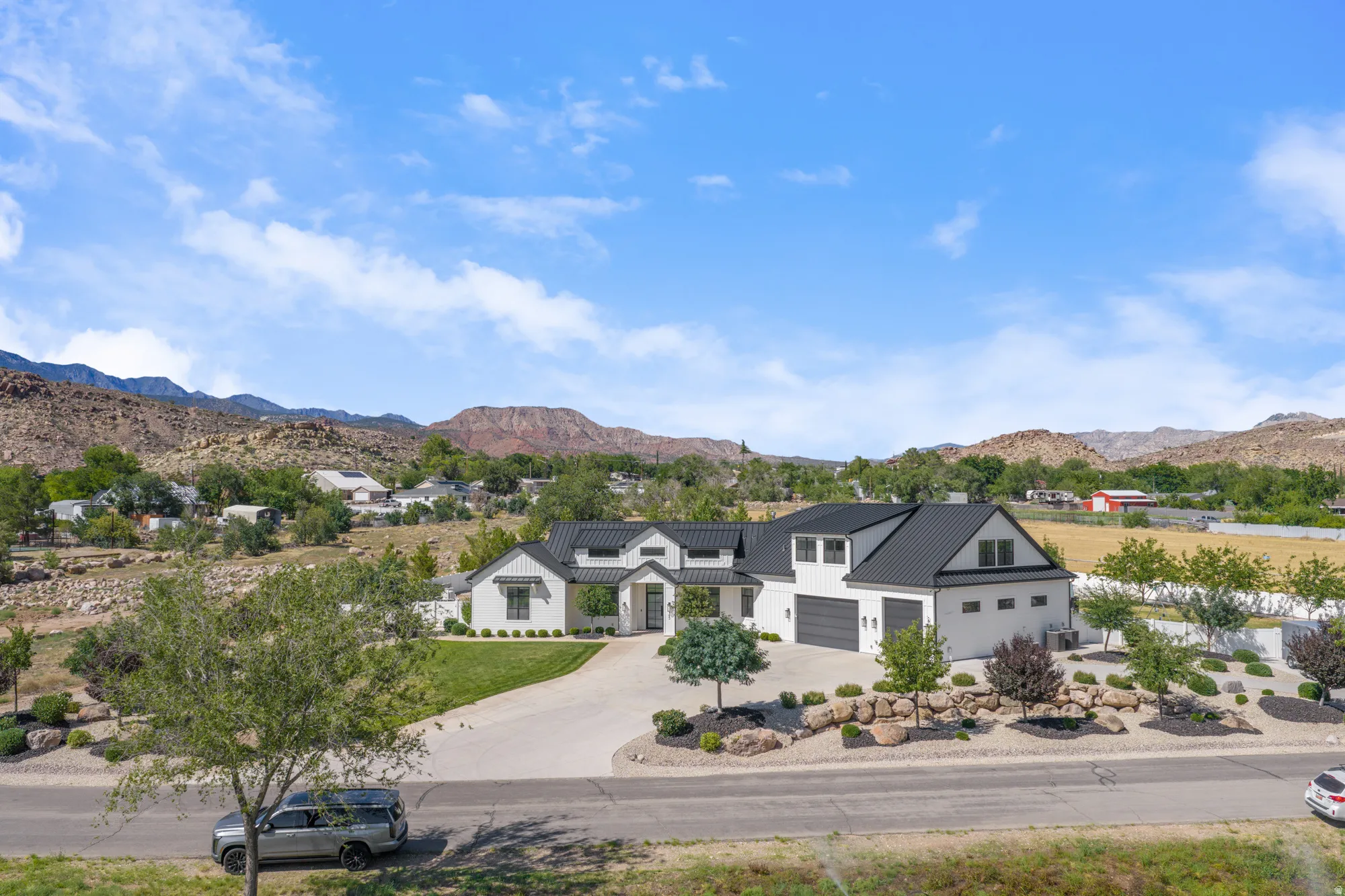 Modern farmhouse-style exterior with white stucco siding and black metal roofing