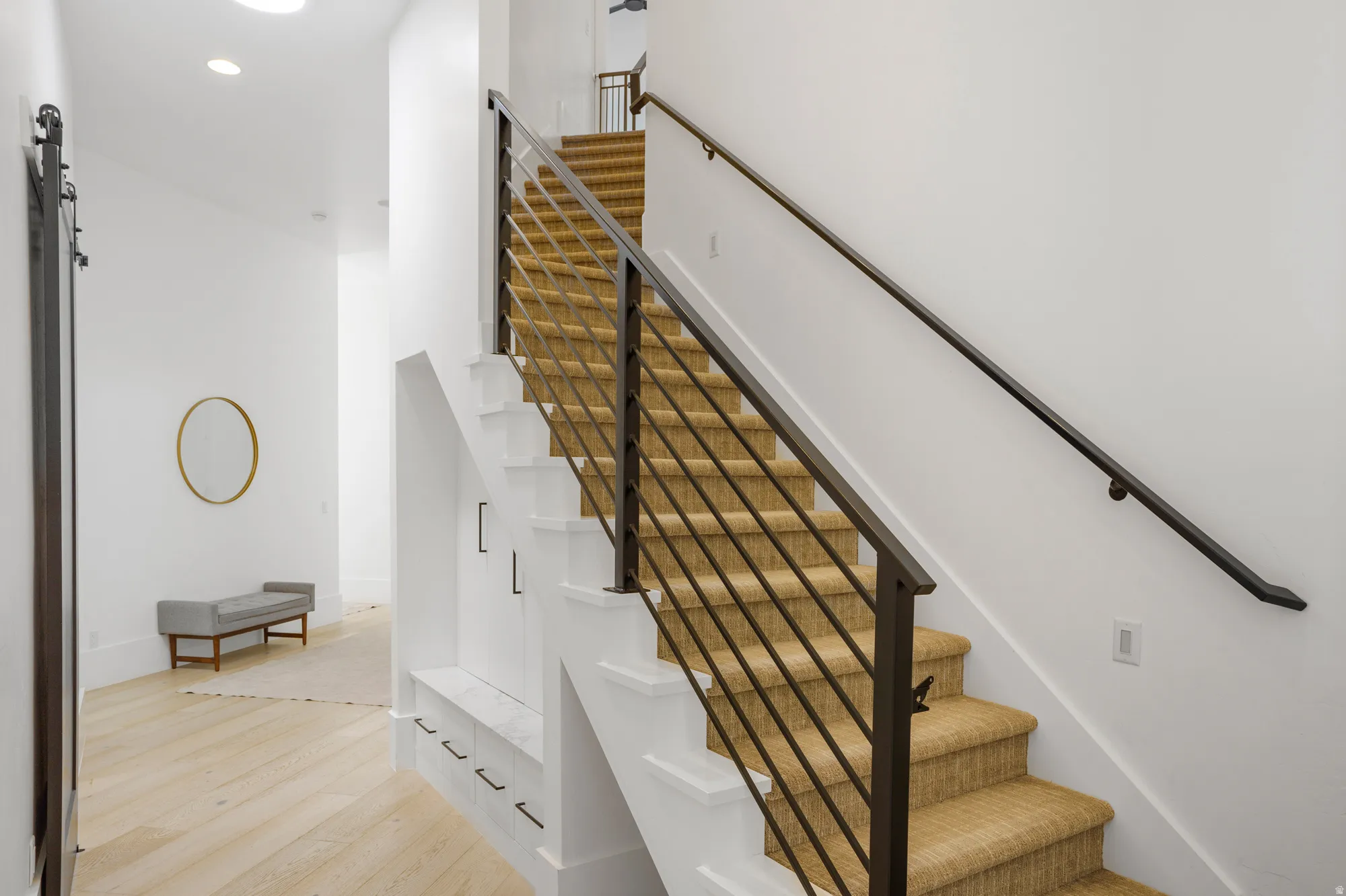 Modern staircase featuring metal railings and carpeted treads