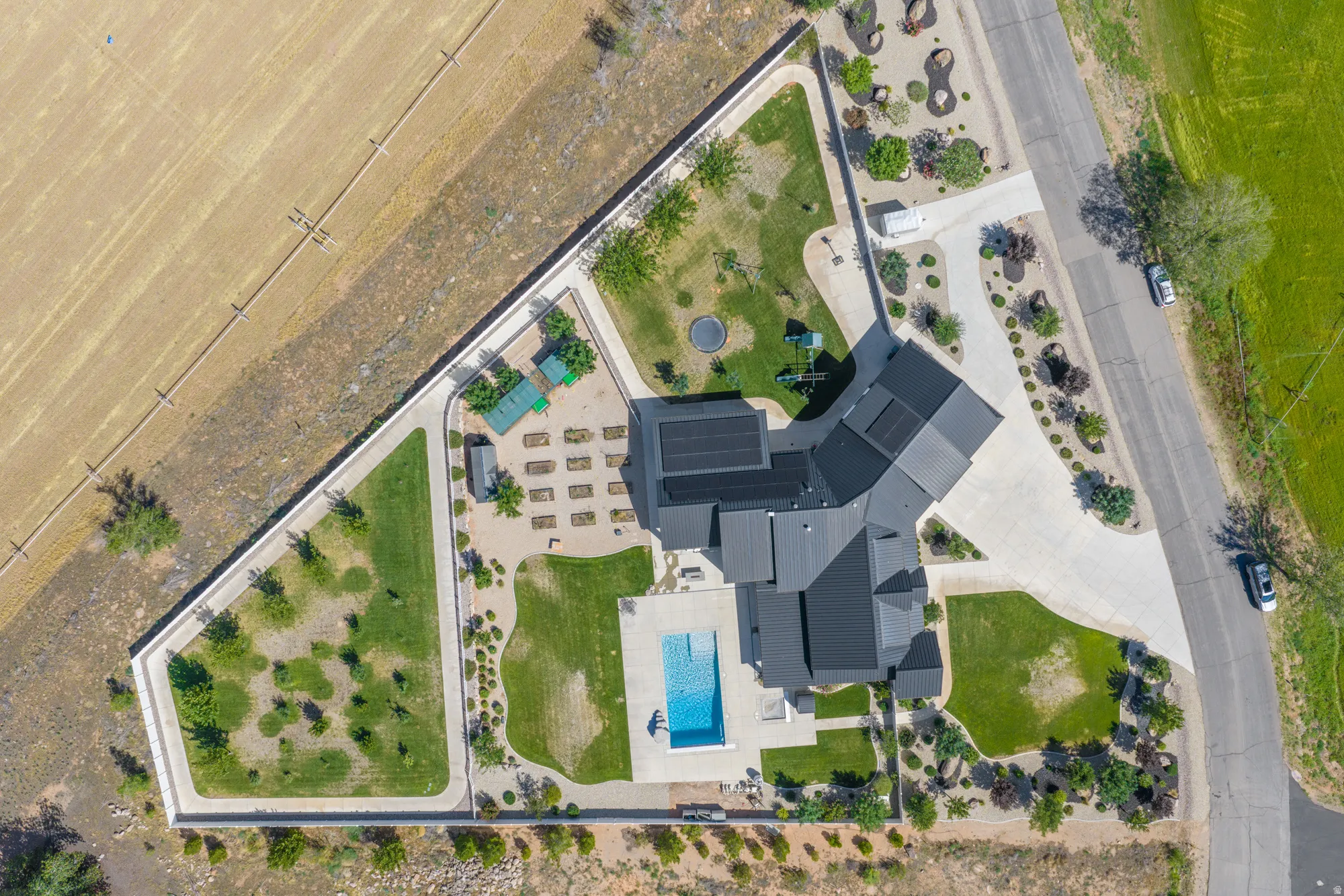Modern residence with striking dark architectural roofline and clean geometric design, set on manicured grounds featuring mature landscaping, established trees, and a resort-style swimming pool