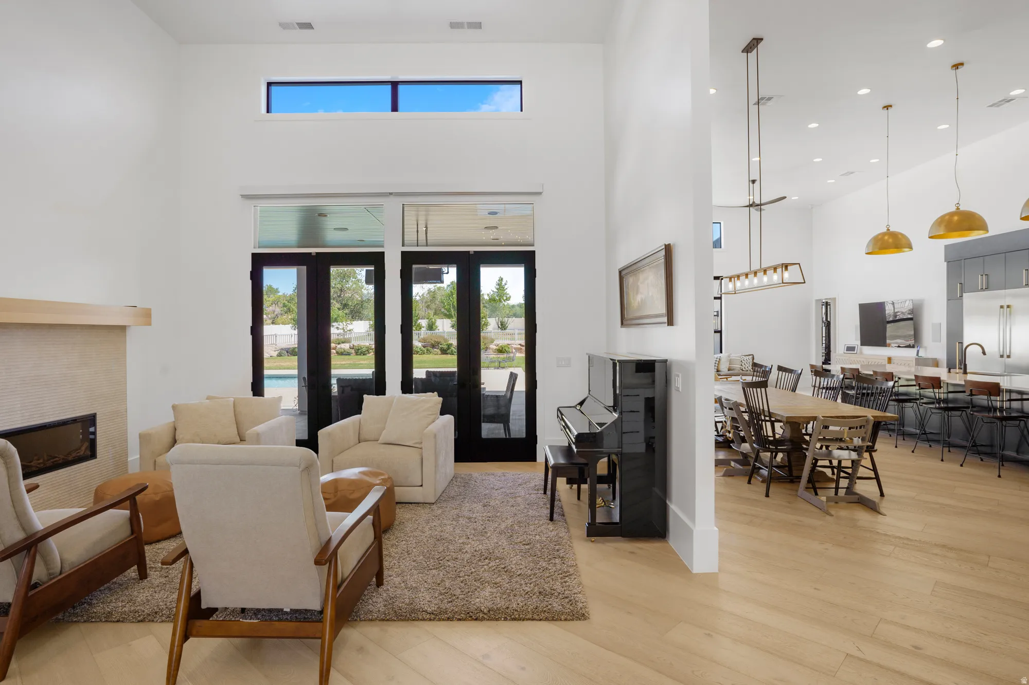 Great room with high ceilings, featuring a fireplace with a stone surround and wood mantel
