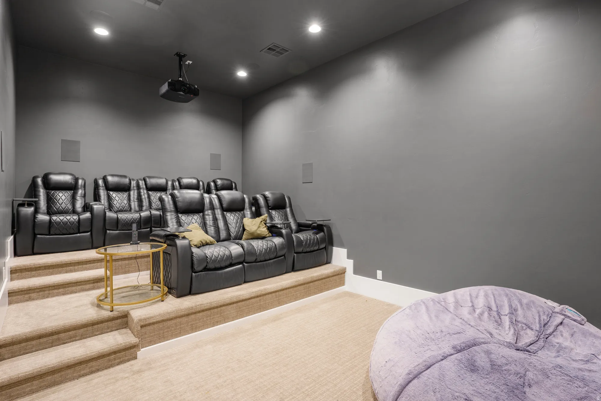 Home Theater Room with tiered seating arrangement featuring multiple rows of black leather recliners with built-in cup holders and accent pillows