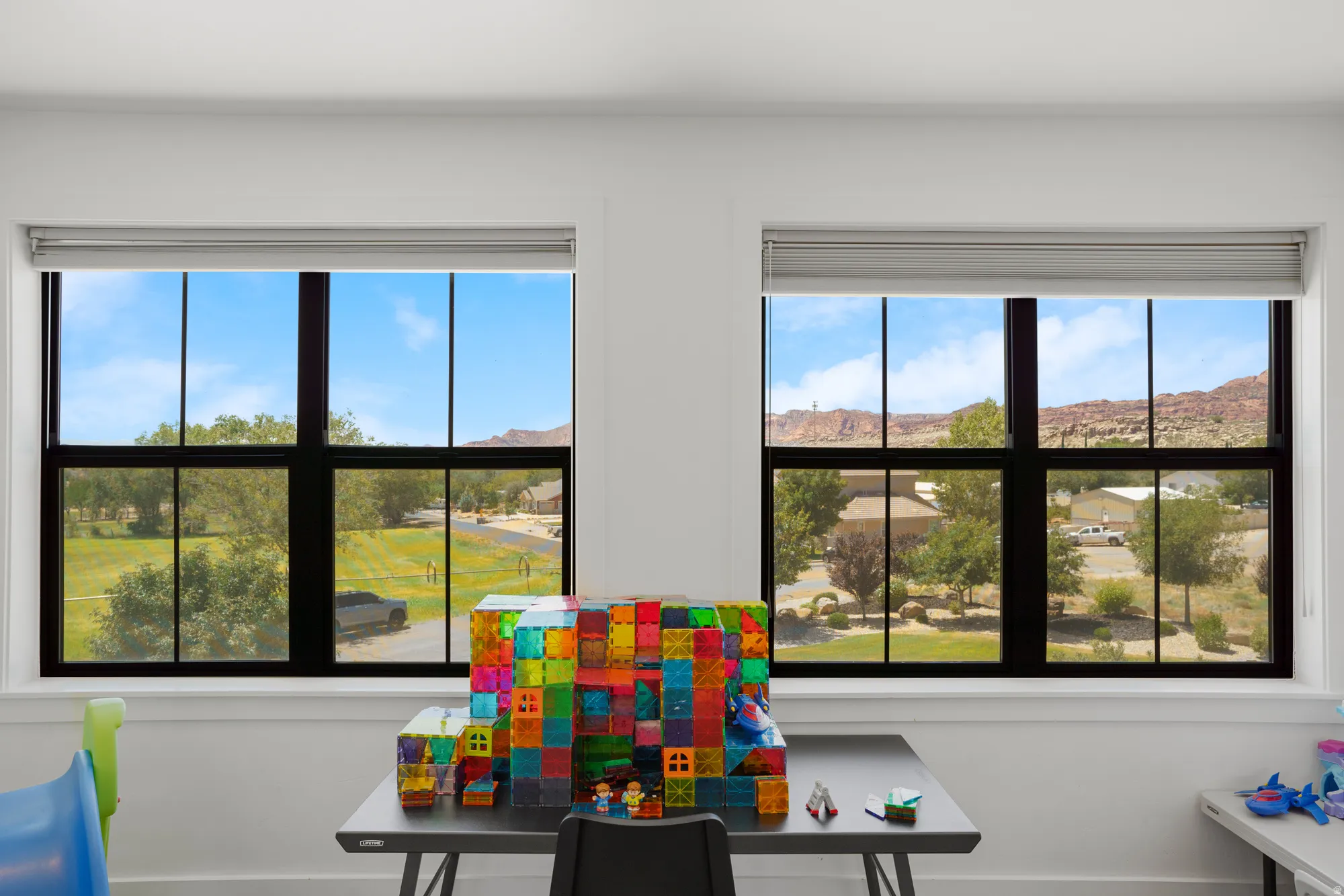 Two large windows with black frames and grilles offer expansive views of the surrounding landscape