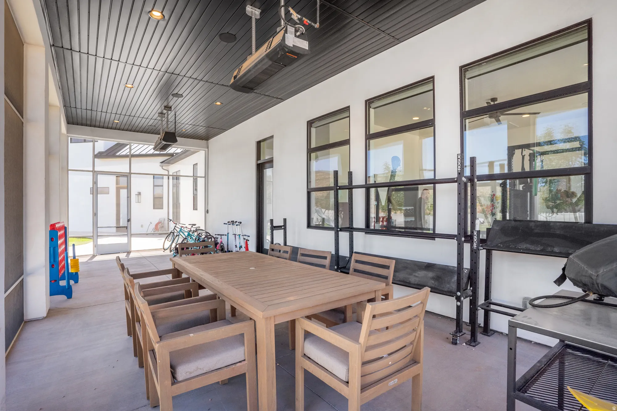 Covered patio featuring a slatted dark ceiling with recessed lighting and mounted heaters