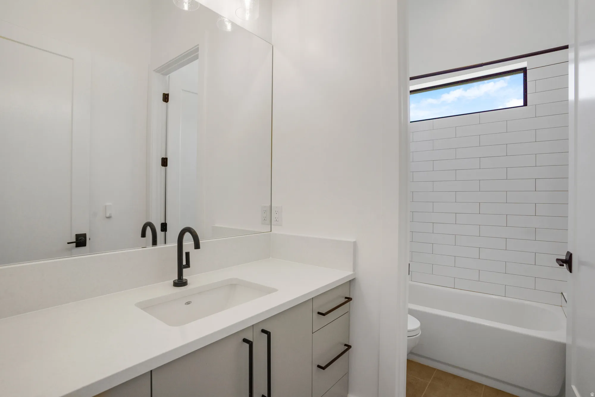 Modern primary bathroom featuring a floating vanity with a rectangular vessel sink, white quartz countertop, and matte black wall-mounted faucet