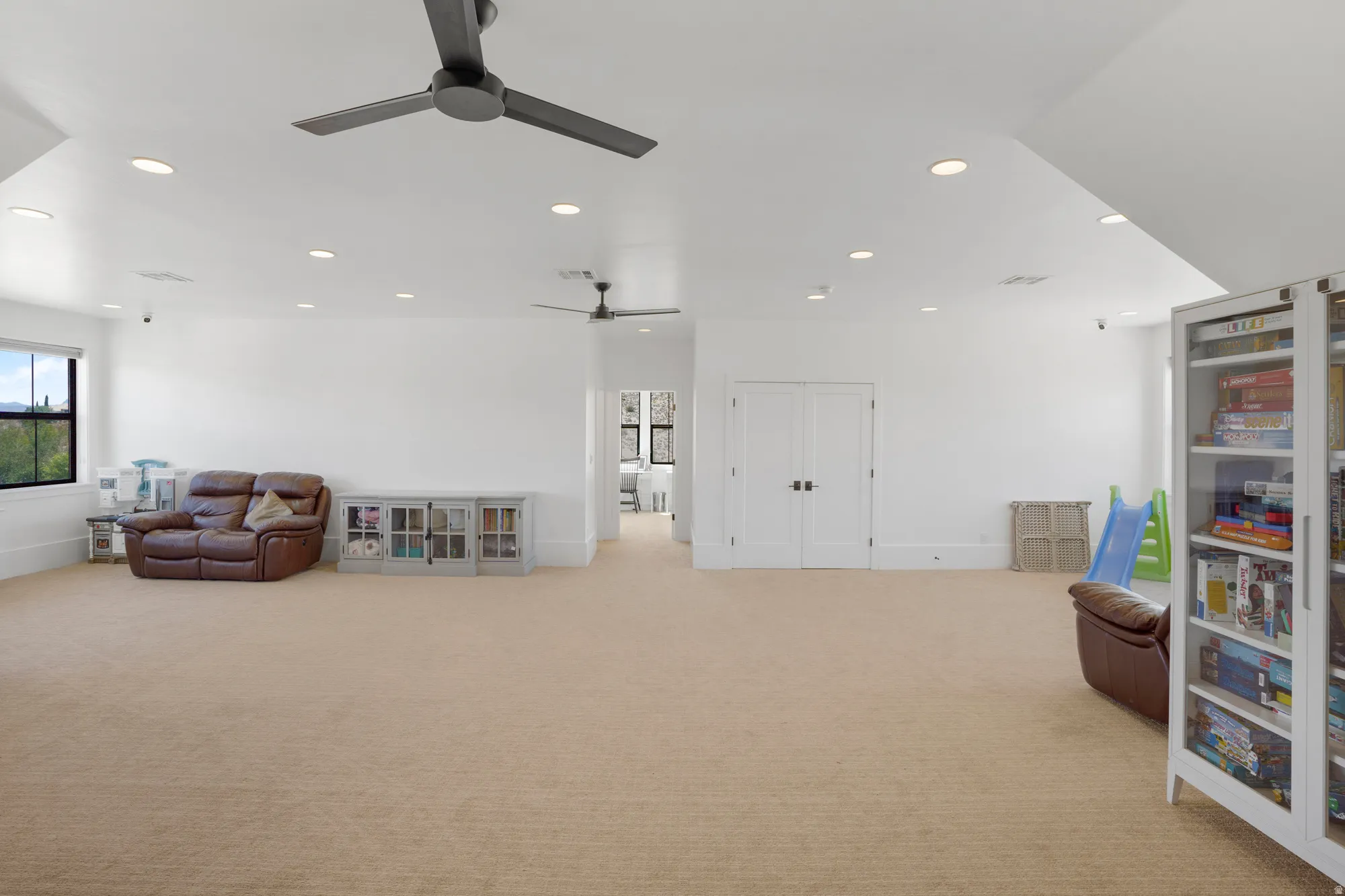 Expansive bonus room featuring soaring vaulted ceilings with recessed lighting and ceiling fan, pristine white drywall finishes, and neutral carpet flooring throughout