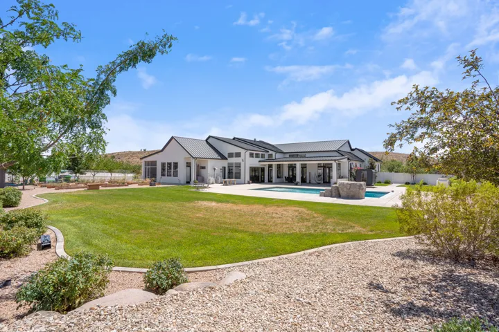 Expansive backyard featuring a manicured lawn, a swimming pool with rock features, and a spacious concrete patio