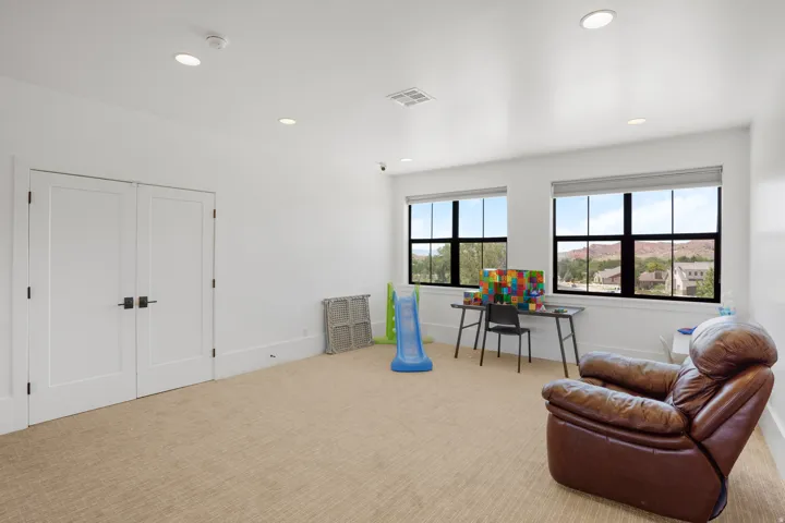 Carpeted room featuring two prominent windows with natural light, recessed ceiling lighting, and crisp white walls