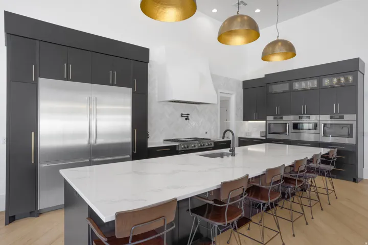 Gourmet kitchen featuring a substantial island with stone countertop, integrated sink, and seating for multiple guests