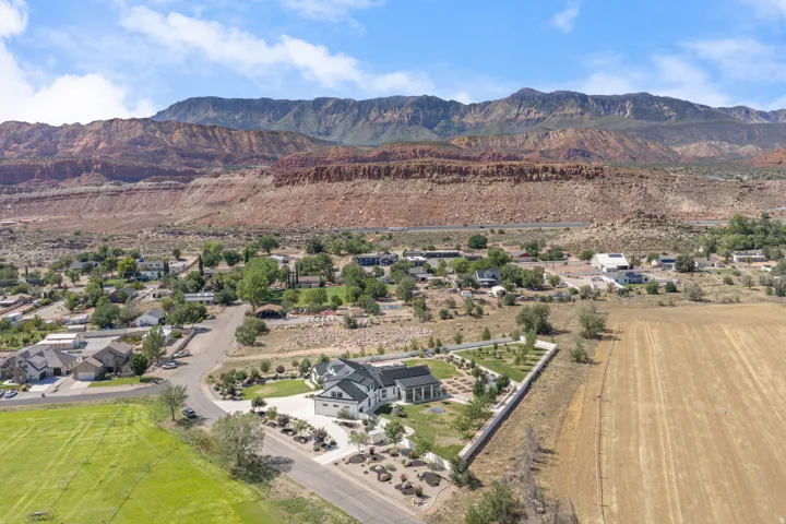 Stunning aerial perspective showcasing this custom residence positioned on expansive grounds with manicured landscaping, mature trees, and irrigated lawn