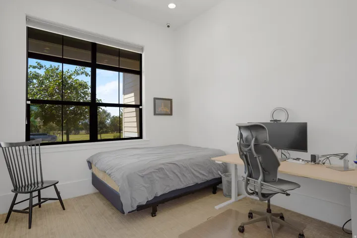 Large multi-pane window with black framing, high ceilings, recessed lighting, white baseboards, and light-toned flooring