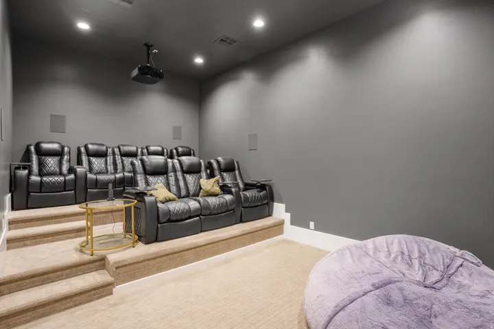 Home Theater Room with tiered seating arrangement featuring multiple rows of black leather recliners with built-in cup holders and accent pillows