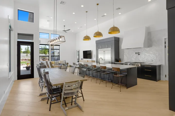 Open-concept living and dining area featuring wood-finish flooring, soaring ceilings with recessed lighting, and brass pendant fixtures