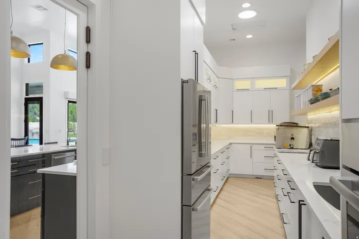 Galley kitchen featuring white cabinetry, integrated stainless steel double oven, perimeter countertops, and wood-finish flooring