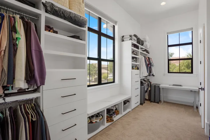 Custom closet system featuring built-in shelving, drawers with matte black hardware, and multiple hanging rods