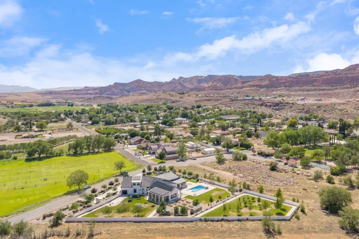 Aerial perspective showcasing a modern residence with a white exterior, a rectangular swimming pool, and a structured landscaping design