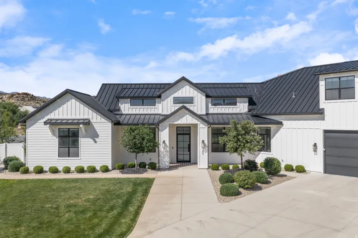 Modern farmhouse residence showcasing a striking white exterior with black metal roof accents, complemented by board-and-batten siding details