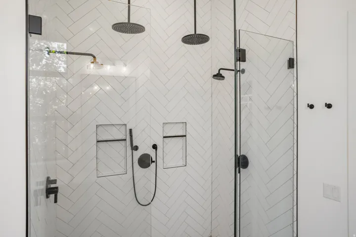 Walk-in shower with clear glass enclosure and matte black fixtures