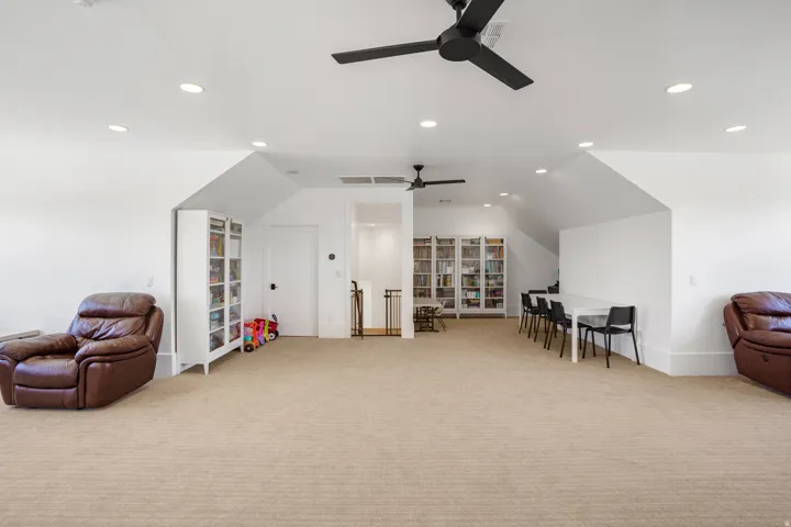 Spacious carpeted room featuring a sloped ceiling and recessed lighting