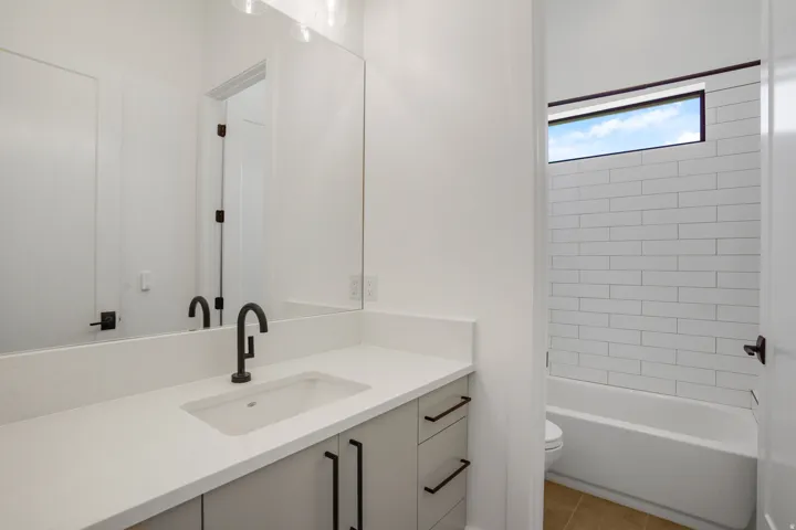 Modern primary bathroom featuring a floating vanity with a rectangular vessel sink, white quartz countertop, and matte black wall-mounted faucet