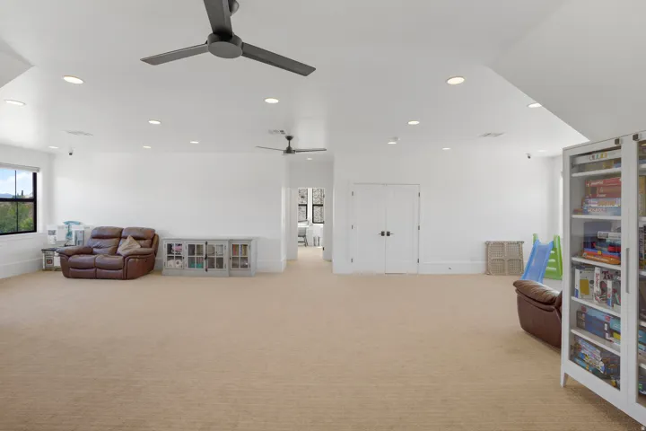 Expansive bonus room featuring soaring vaulted ceilings with recessed lighting and ceiling fan, pristine white drywall finishes, and neutral carpet flooring throughout