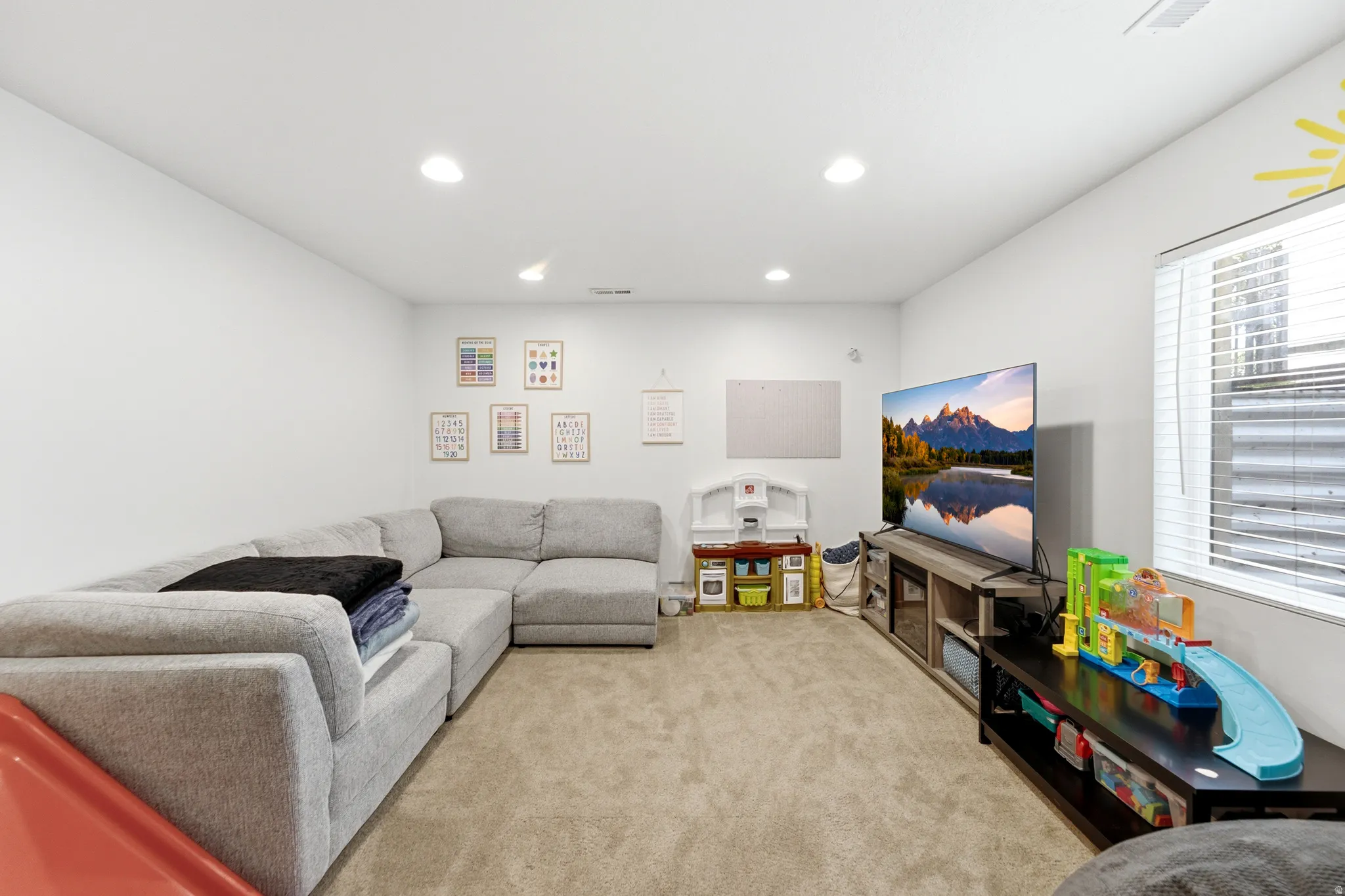 Expansive carpeted room featuring white walls and recessed lighting