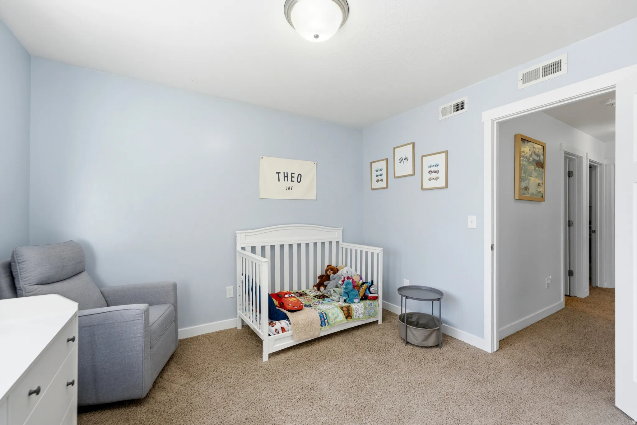 Bright nursery featuring soft blue walls, recessed ceiling lighting, and neutral carpet flooring