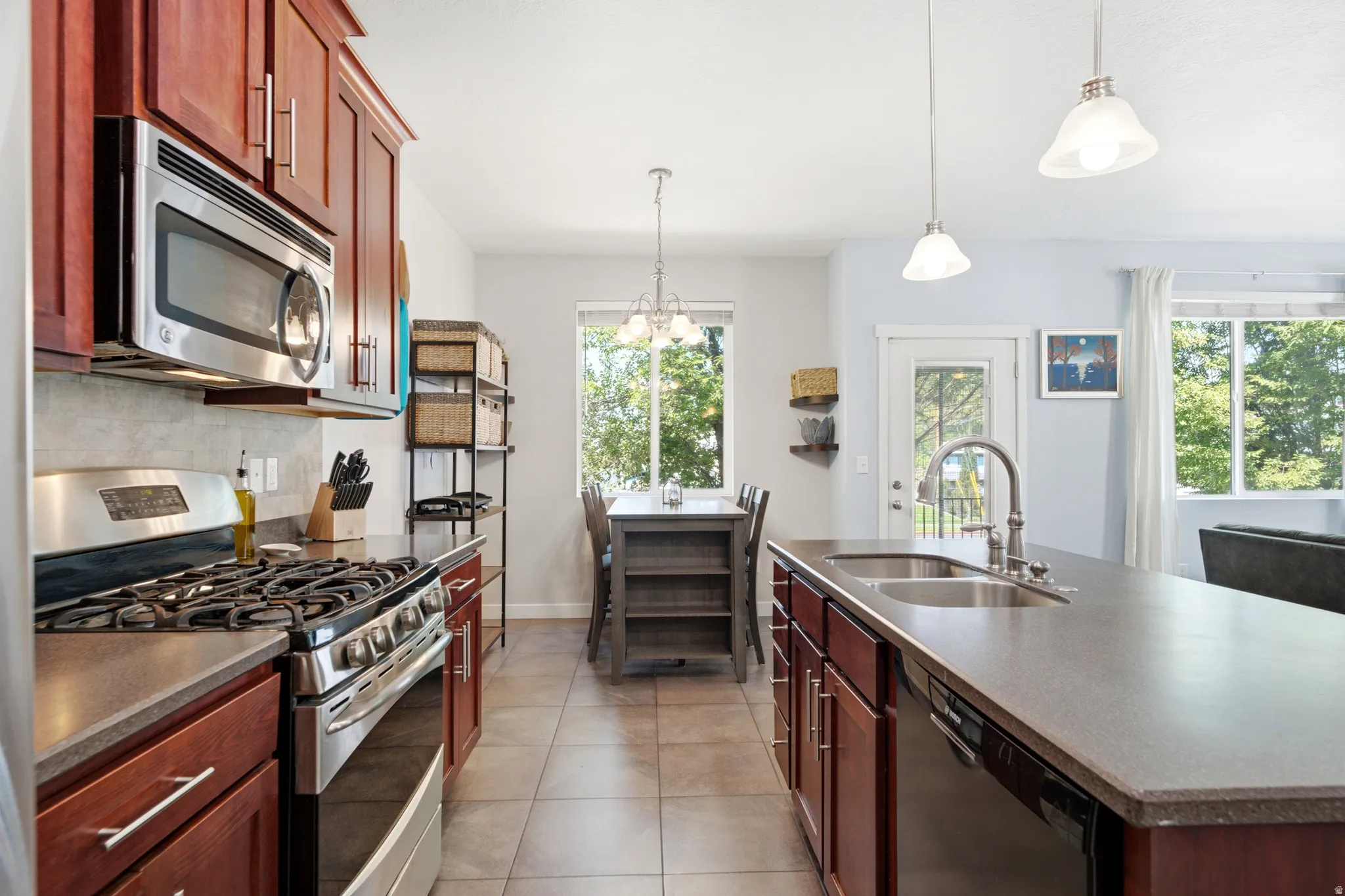 Chef's kitchen featuring rich wood cabinetry, stainless steel gas range with professional-grade hood, granite countertops, and a spacious island with seating