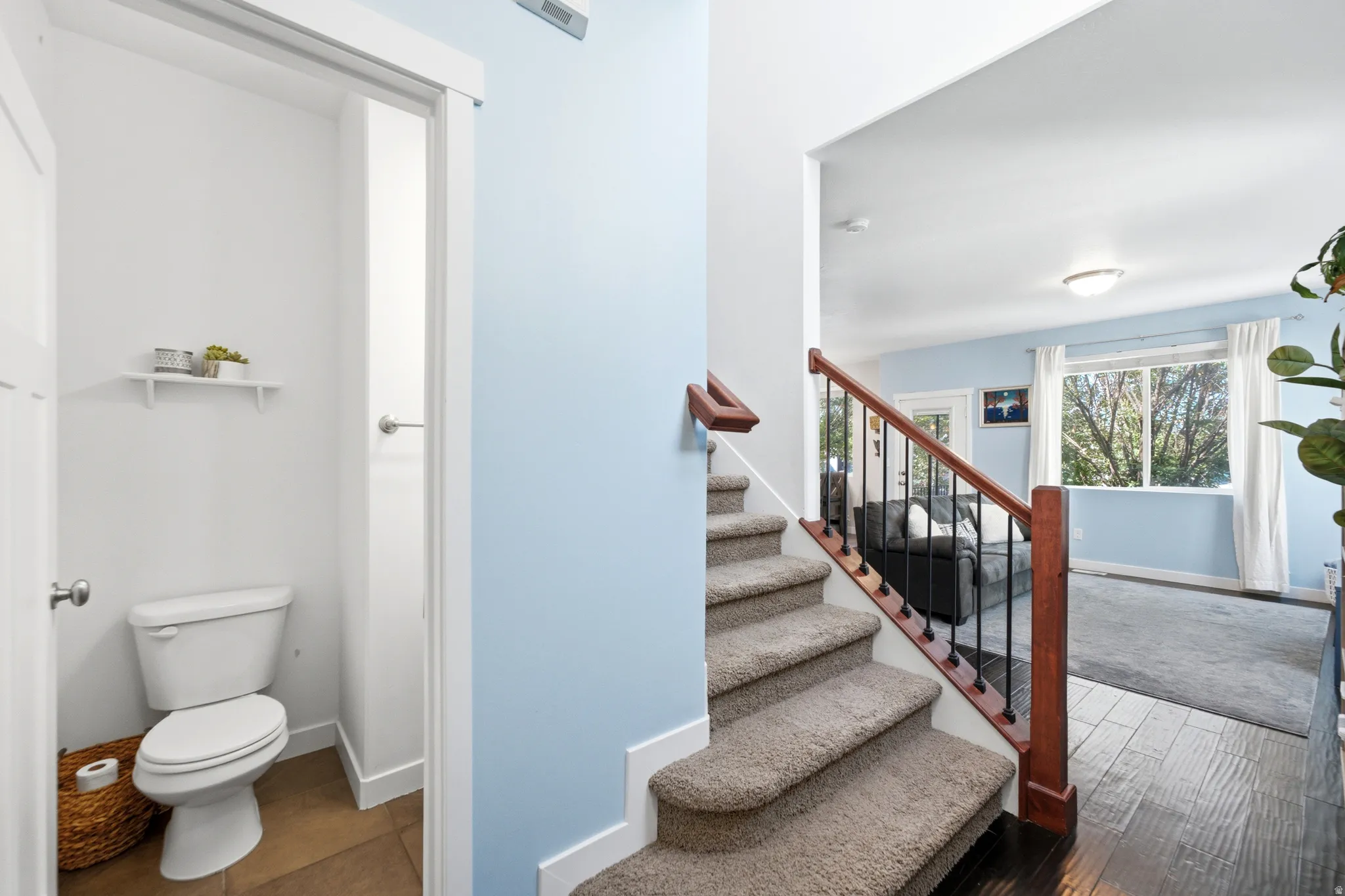 Bright staircase with wood-finish treads and mahogany handrail features a light-filled landing and direct access to multiple levels
