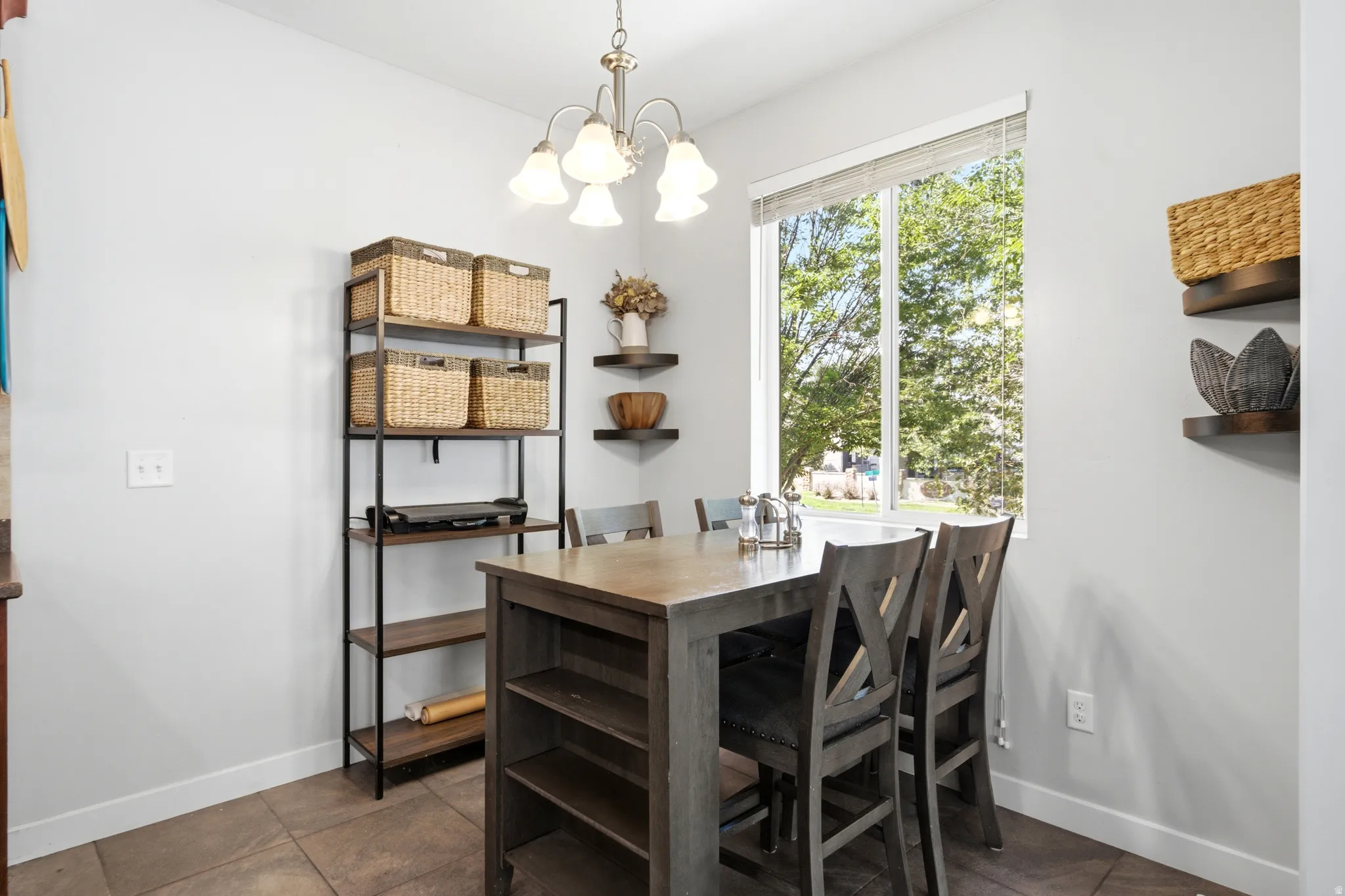 Dining area featuring a wood-finish table with storage shelving, complemented by X-back dining chairs and a coordinating black metal shelving unit with woven basket organization