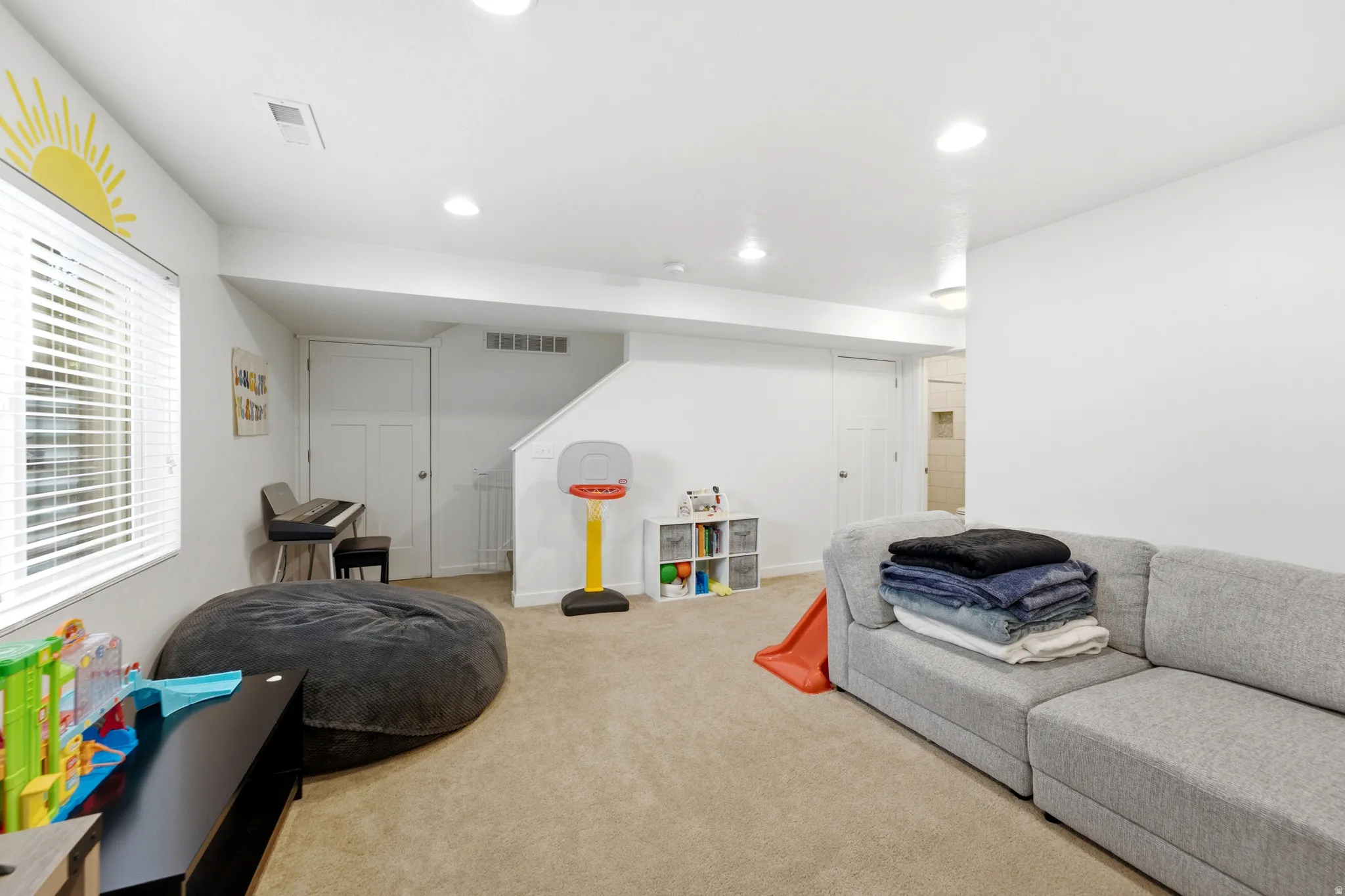 Spacious finished basement recreation room featuring neutral carpeting, recessed lighting, and ample open floor plan