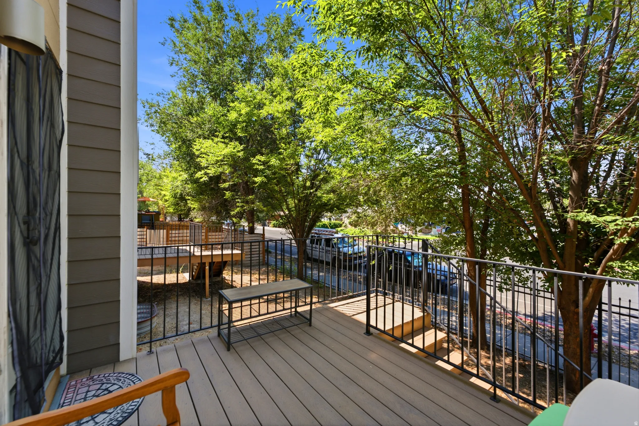 Spacious composite deck featuring composite wood-finish decking, black metal railing with horizontal balusters, and mature tree canopy overhead