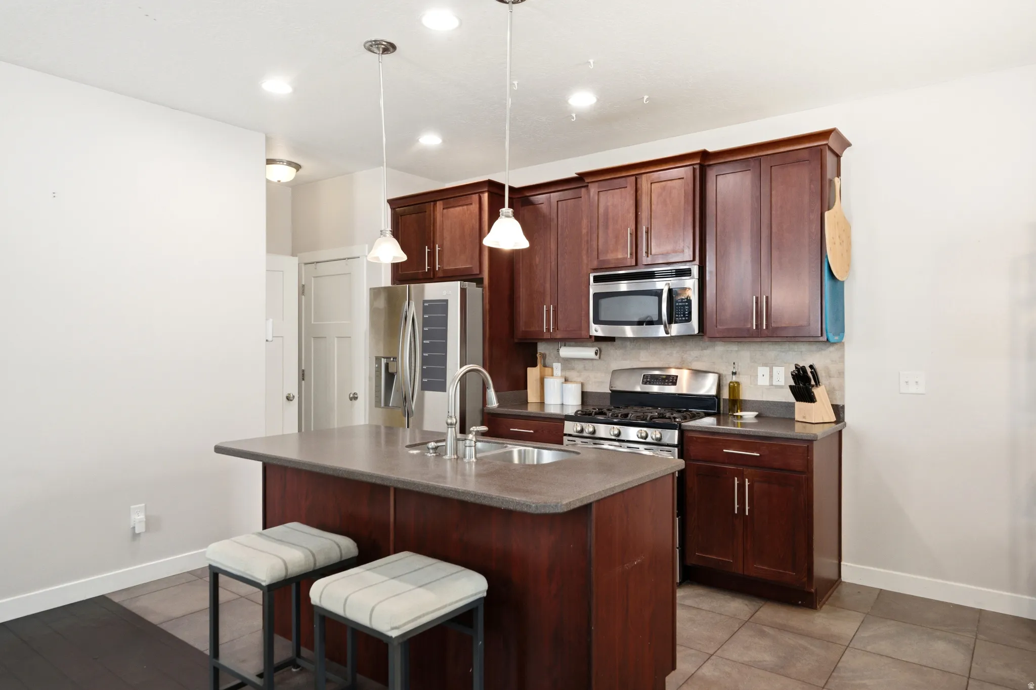 Modern kitchen featuring rich wood-finish cabinetry with stainless steel appliances, including a gas cooktop and built-in microwave