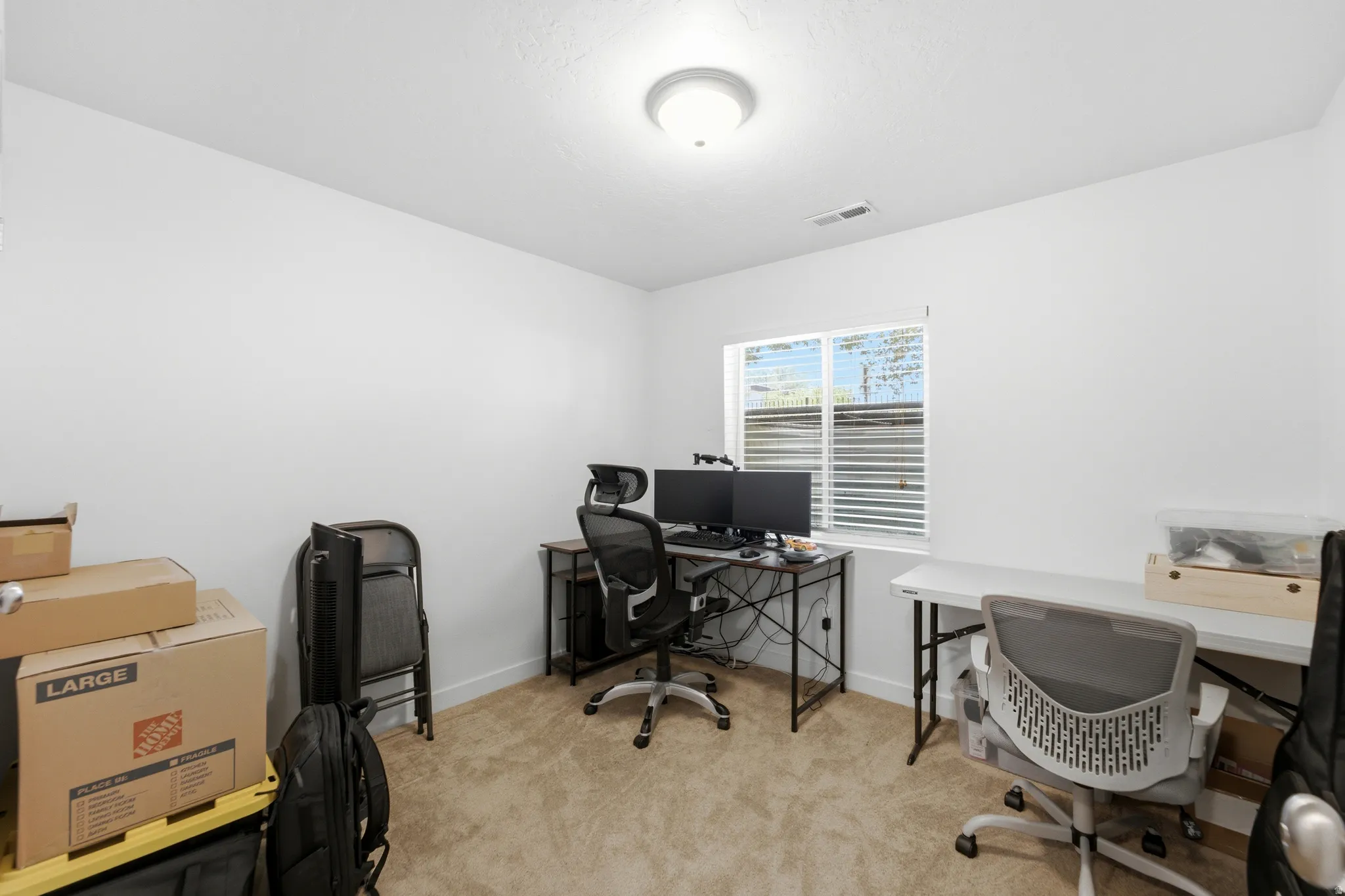 Versatile home office featuring neutral carpeting, recessed ceiling lighting, and large windows with plantation shutters providing natural illumination