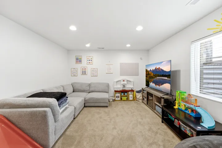 Expansive carpeted room featuring white walls and recessed lighting