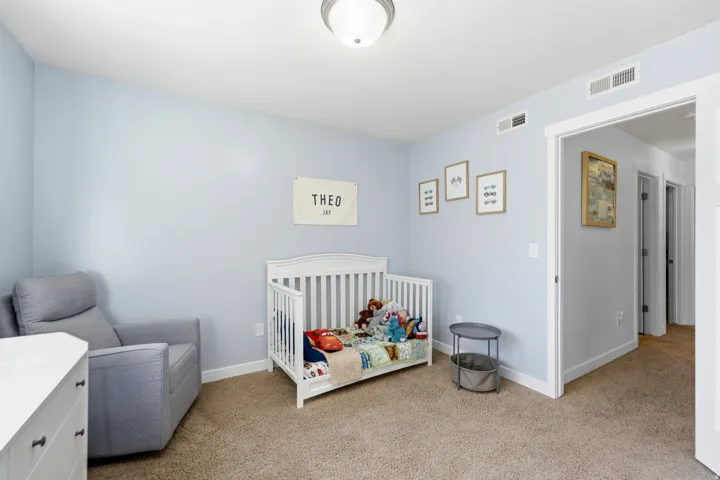 Bright nursery featuring soft blue walls, recessed ceiling lighting, and neutral carpet flooring
