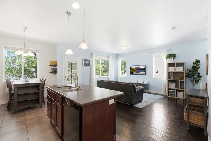 Open-concept living space featuring a large kitchen island with dark wood cabinetry and stainless steel countertop, pendant lighting, and hardwood flooring throughout