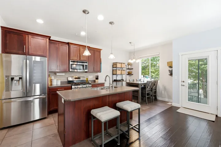 Kitchen featuring stainless steel appliances, rich wood cabinetry, a center island with pendant lighting, and tile flooring