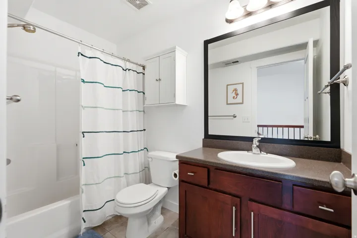 Spa-inspired bathroom featuring a rich wood-finish vanity with dual sink configuration, ample storage cabinetry, and a large framed mirror with integrated lighting
