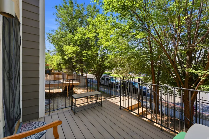 Spacious composite deck featuring composite wood-finish decking, black metal railing with horizontal balusters, and mature tree canopy overhead