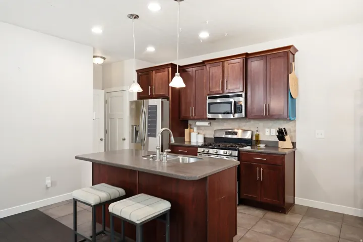 Modern kitchen featuring rich wood-finish cabinetry with stainless steel appliances, including a gas cooktop and built-in microwave