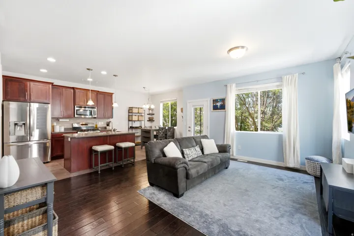 Open-concept living space featuring a dark wood-finish floor throughout, complemented by light blue accent walls and abundant natural light from multiple windows
