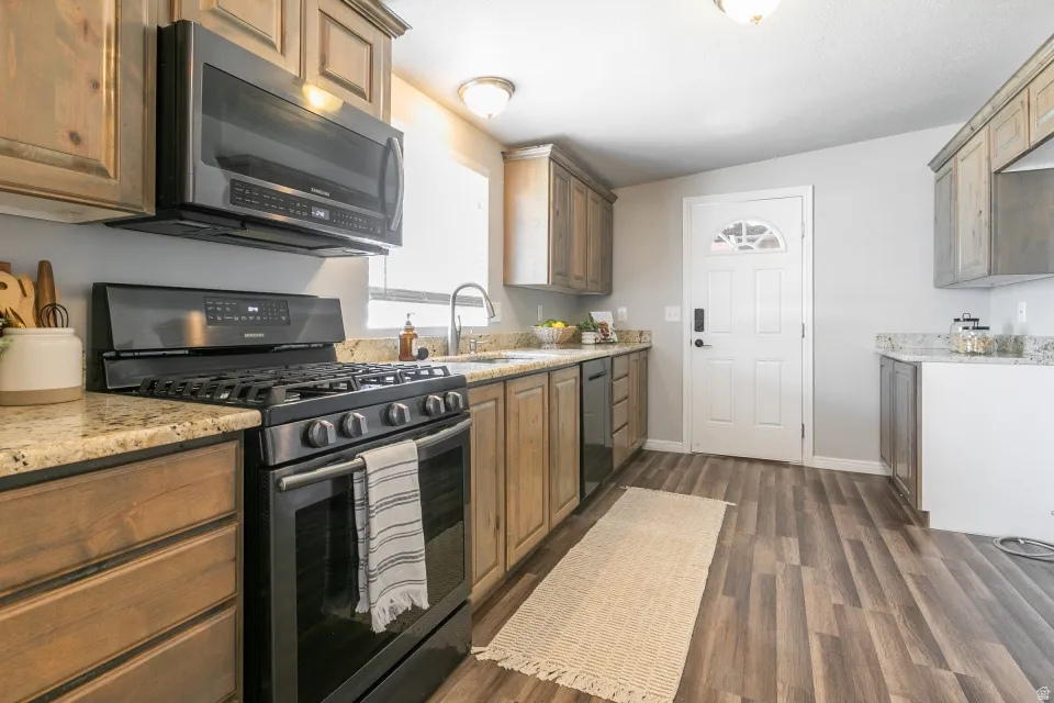 Kitchen featuring wood-finish cabinetry, speckled countertops, and wood-finish flooring