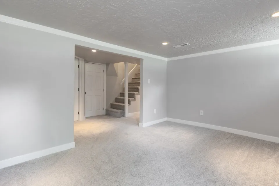 Spacious finished basement featuring pristine carpet flooring, recessed ceiling lighting, and clean drywall construction