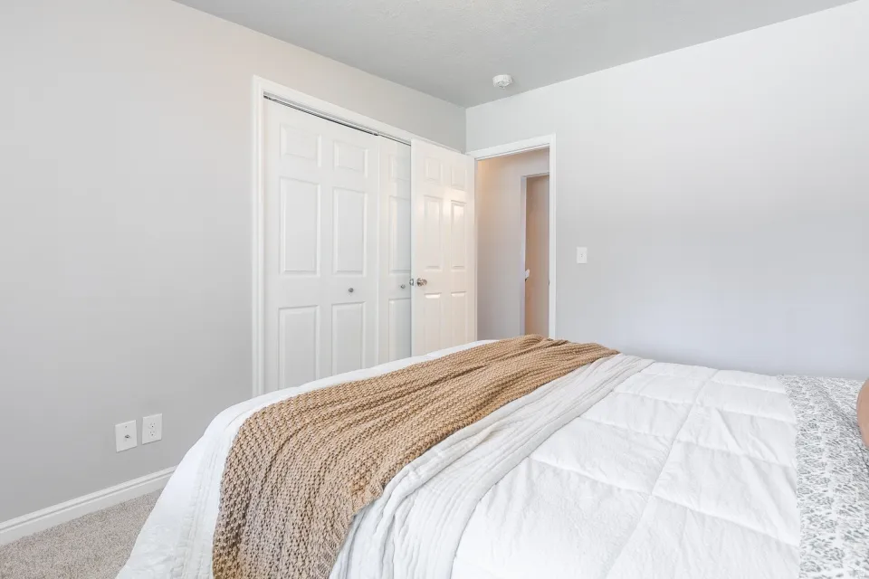 Bright bedroom featuring neutral wall finishes, carpeted flooring, and dual closet storage with six-panel doors
