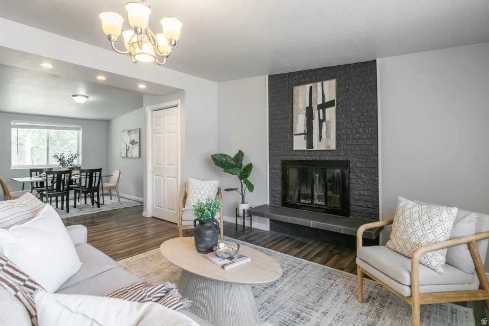 Living area with wood-finish flooring and a contemporary fireplace featuring a dark brick surround and hearth